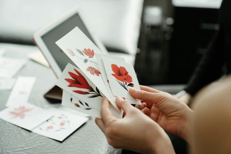 Close-up of hands holding red flower sketches in a tattoo studio.